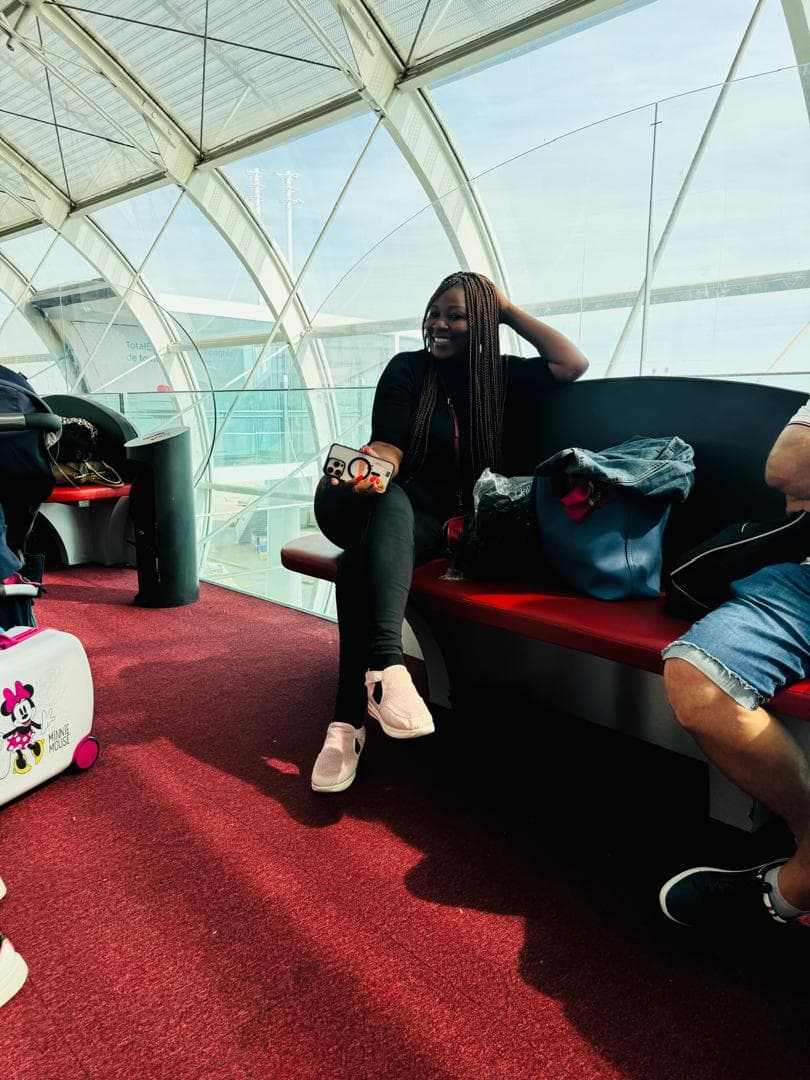Malorfa smiling at an airport terminal with travel bags nearby