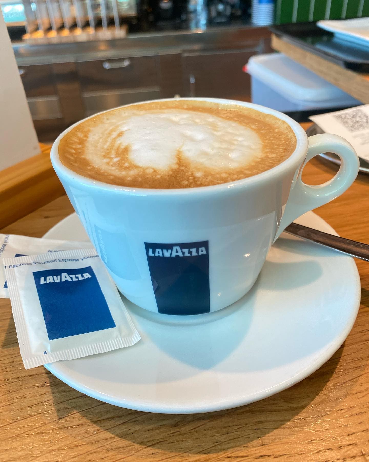 A Lavazza coffee on a wooden café table