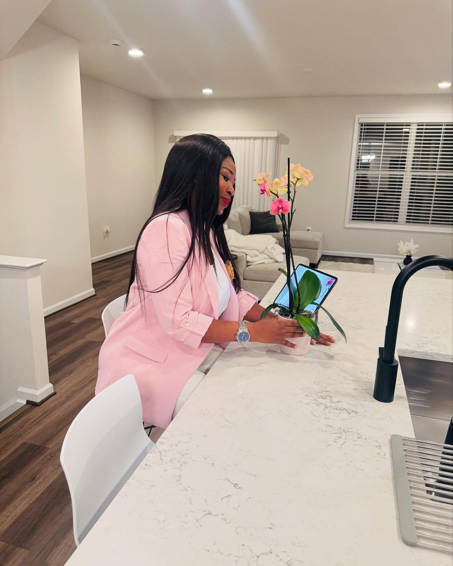 Malorfa Aryee in a pink blazer tending an orchid at home